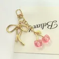 Adorable porte-clés cerise rose translucide avec élégant nœud doré pour sacs à main - Grand nœud papillon cerise transparente / Rose + Or