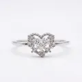 Close-up of a delicate heart-shaped ring featuring a center stone and floral pave details. - Silver