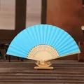 Blauer Fächer aus Papier mit geschnitztem Bambusgestell auf Holzständer - See Blau