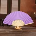 Purple folding paper fan with bamboo ribs on a wooden display stand for DIY painting - Deep purple