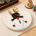 Süßer Weihnachtswichtel-Besteckhalter mit weißem Bart auf einem weißen Teller - Schneemann