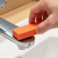 Détail d'une gomme antitartre orange nettoyant un robinet de salle de bain en inox - Rectangulaire / Orange