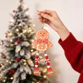 Hand holding a detailed wooden gingerbread man Christmas ornament with long bead legs. - Brown and White
