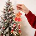 Hand holding a wooden gingerbread man ornament with beaded legs in front of Christmas tree. - Brown Red