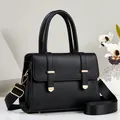 Detail view of black pebble grain handbag featuring elegant gold-tone hardware finish - Black