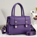 Detailed view of a purple leather handbag with gold-toned hardware and wide shoulder strap - Purple