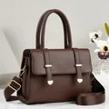 Detailed view of dark brown pebble grain handbag showing elegant dual handles and gold accents - Coffee