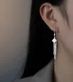Eleganti orecchini lunghi in argento con nappe e borchia a rombo su modella asiatica - Infilatore per Orecchie Quadrato Con Diamanti