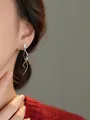 Eleganti orecchini pendenti a spirale in argento con zircone rettangolare su modella - Orecchini a Onda in Strass Quadrato
