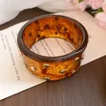 Nahaufnahme eines breiten Schildpatt-Acrylarmbands mit polierten Goldnieten-Akzenten - #42 Silberstift - Braun - Gold - Nieten-Stil