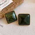 Nahaufnahme von dunkelgrünen, marmorierten Acrylohrringen im eleganten Goldrahmen - Stil mit Silber-Ohrstecker / Dunkelgrün