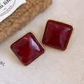 Nahaufnahme von quadratischen roten Marmor-Acryl-Ohrringen mit goldenem Metallrahmen - Stil mit Silber-Ohrstecker / Rot