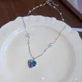 Elegant blue heart zircon and white pearl necklace displayed on a cream ceramic plate. - Necklace / Necklace (Silver/White/Blue)