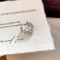 Close-up van een bloemvormige oorklem met parels en zirkonia op getextureerd papier - Bloem Parel Oorclips / Enkel Stuk / Zilver
