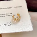 Gedetailleerde close-up van 18k vergulde oorklem met zirkonia bloemen en parels. - Bloem Parel Oorclips / Enkel Stuk / Goud