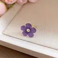 Detalle de un anillo ajustable de flor en esmalte púrpura con elegantes tonos dorados. - Anillo / Púrpura