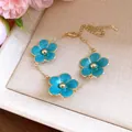Detailed shot of an exquisite turquoise enamel flower bracelet with a gold adjustable chain. - Bracelet / Blue