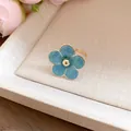 Close-up of a delicate blue enamel flower ring on a beige textured tray - Ring / Blue