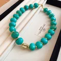 Detailed view of a turquoise beaded necklace with gold accents in a jewelry tray. - Gold-Cyan (79#)