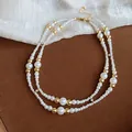 Detail van een retro dubbellaagse parelketting met gouden kralen en sprankelende strassteentjes. - Dubbellaagse Sleutelbeen Ketting / Goud+Wit