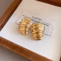 Primer plano detallado de pendientes vintage dorados con textura geométrica en estuche - Dorado