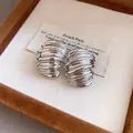 Vista detallada de pendientes geométricos vintage plateados en una elegante caja de joyería de lujo - Plateado
