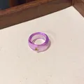 High-angle detail shot of a purple transparent resin ring featuring a small embedded crystal. - Purple