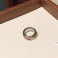 Detailweergave van grijze doorschijnende harsring met een klein rood kristal. - Grijs