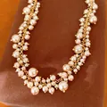 Elegante halsketting in hofstijl met goudkleurige kettingen en crèmekleurige parelkwastjes. - Ketting / Goud-Bruin