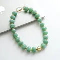 Dettaglio delle perle in acrilico marmorizzato verde e accenti dorati sulla collana. - Verde