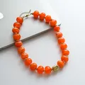 Primo piano di una collana vintage di perle acriliche marmorizzate arancioni con tocchi d'oro. - Arancione