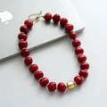 Dettaglio di perle acriliche rosse marmorizzate e ciondolo geometrico dorato vintage. - Rosso