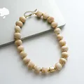 Dettaglio di una collana retrò con perle in acrilico marmorizzato e inserti dorati - Cachi