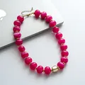 Vista dettagliata delle perle in acrilico marmorizzato fucsia e accenti dorati su collana retrò - Rosso rosa