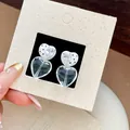 Detaillierte Makroansicht von klaren Herzohrringen mit Zirkonia und weißem Polka-Dot-Design - Doppelschicht Schwarz Punkte Tropföl Große Klar Herz Hängeohrringe (Stil 10)