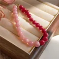 Close-up of pink and red dual-tone acrylic beaded necklace in a wooden jewelry tray - Pink