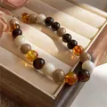 Macro view of glossy acrylic beaded necklace in warm amber and earthy tones. - White And Coffee