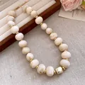Close-up detail showing a cream oval acrylic bead necklace with elegant gold spacers. - Gold-Tone Pendant Cream Oval Bead Necklace (81#) / 81# Necklaces - Gold - Khaki