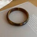 Close-up macro view of vintage brown resin bangle with glossy finish on book - Closed Round Bangle Style (52#)
