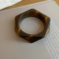 Detail view of a vintage hexagonal tortoiseshell resin bangle resting on a book page - Hexagonal Geometric Style (51#)