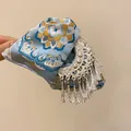 Primo piano di un fermaglio per capelli etnico con tessuto floreale blu e nappe d'argento - 17# Pinza in Raso Etnico di Lusso / Blu