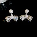 Primer plano detallado de pendientes de lazo con circonitas y perlas elegantes - Pendientes de perlas con lazo / Plateado