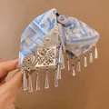 Detail van vintage blauw bedrukte haarklem met zilveren bloemen en kwastjes versiering - Wit en Blauw