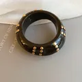 Close-up of black resin bangle with gold stud rivets on a minimalist background. - Multi-row Studded Wide Style / 66# Bangle Gold Brown