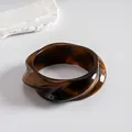 Close-up of a vintage brown resin bangle featuring an amber-like swirl and geometric twist. - Style 3 (Twisted Geometric Coffee)