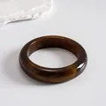 Close-up of a vintage amber resin marbled bangle on a minimalist white stone background - Style 10 (Classic Circle Coffee)