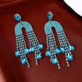 Close-up view of elegant turquoise rhinestone teardrop tassel earrings with sparkling detail - Blue