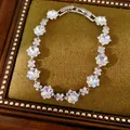 Primer plano de pulsera plateada con cristales de circonita en forma de flor irisada. - Plateado-Azul Blanco