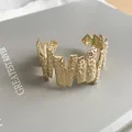 Close-up detail of a gold-colored textured open cuff bracelet with irregular jagged design - Hammered Geometric Style / Gold