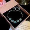 Close-up of 18k gold plated bracelet with sparkling blue zircons in a pink gift box. - Style 7